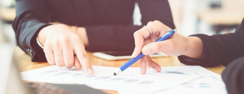 Two people pointing at a piece of paper on a table