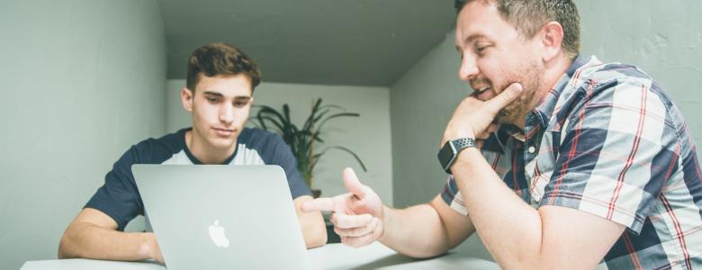 Two men sitting in front of a laptop